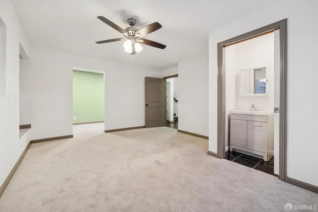 a view of an empty room with wooden floor and stairs