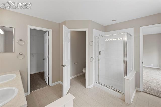 6725 Akron Road Colorado Springs, CO 80923 - Photo 26 of 50 Bathroom with tile patterned floors, walk in shower, and double vanity