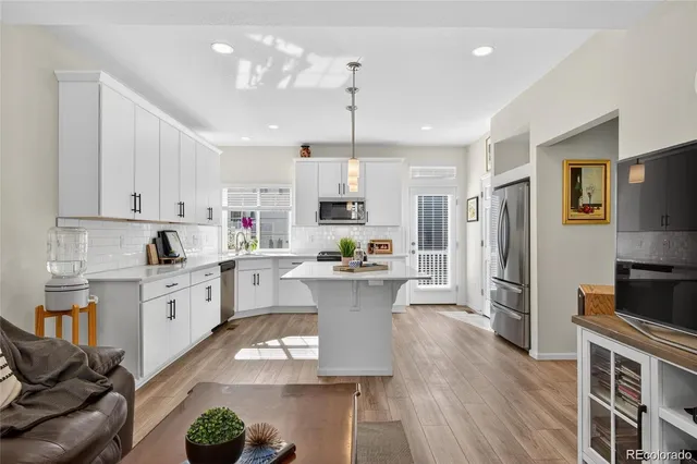a kitchen with kitchen island a white counter top space a sink stainless steel appliances and cabinets