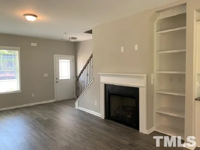 a view of an empty room with wooden floor fireplace and a window