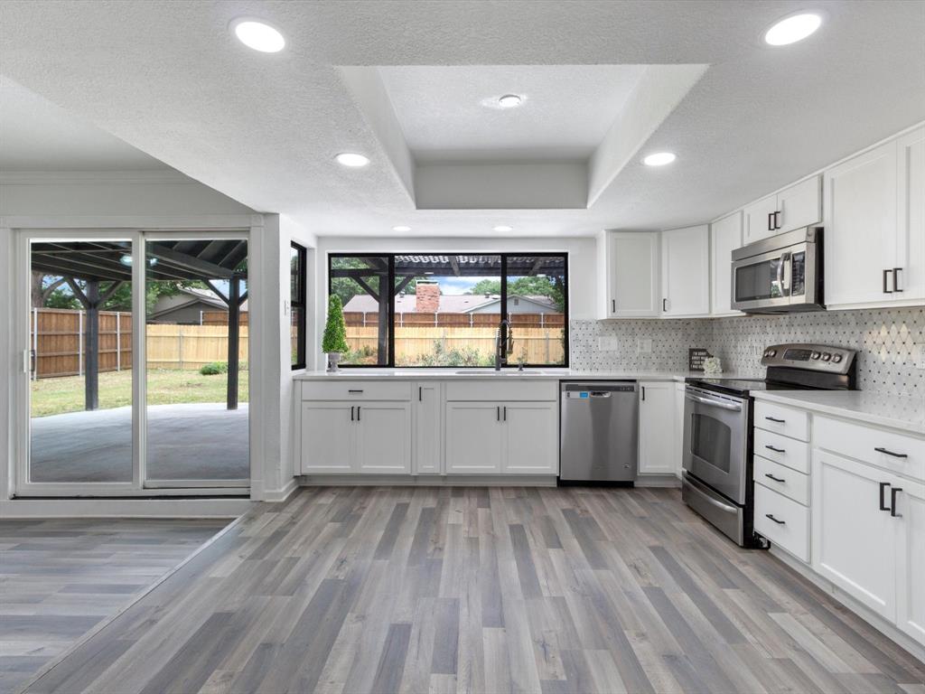 a kitchen with stainless steel appliances granite countertop a stove a sink and a microwave oven with white cabinets