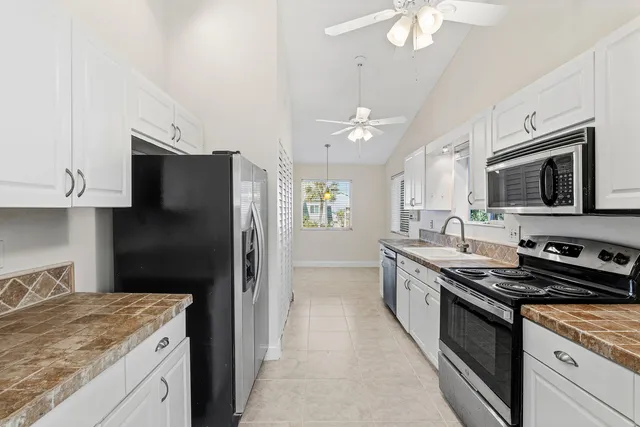 a kitchen with stainless steel appliances granite countertop white cabinets a stove a sink and a white refrigerator