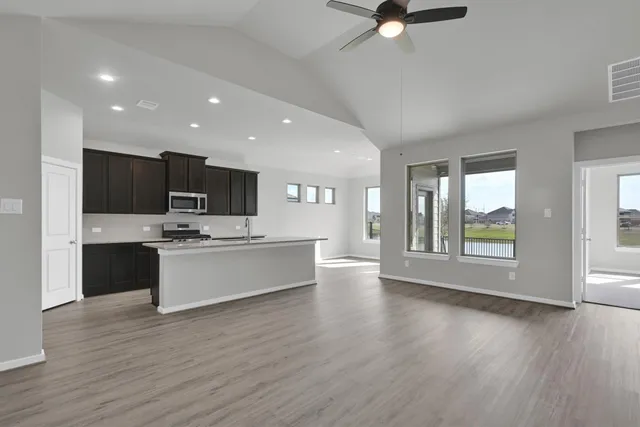 a large kitchen with a large counter top a sink stainless steel appliances and cabinets