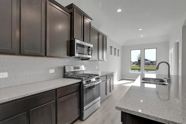 a kitchen with stainless steel appliances granite countertop a sink a stove and a microwave