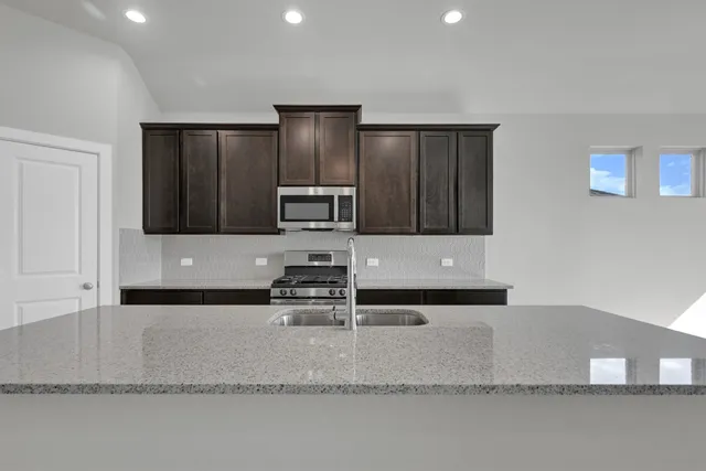 a kitchen with granite countertop a refrigerator and a stove top oven