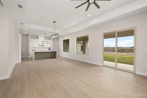 a view of an empty room with a window and kitchen view