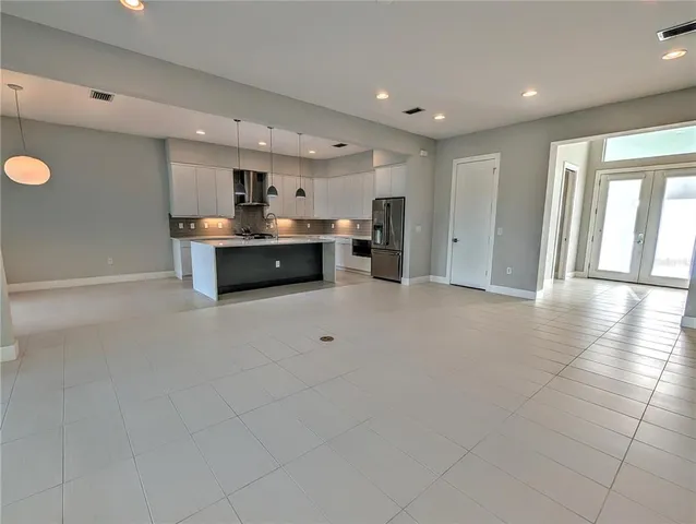 a living room with stainless steel appliances furniture a window and a kitchen view