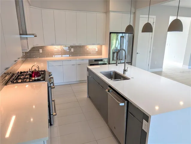 a kitchen with stainless steel appliances granite countertop a sink and a refrigerator