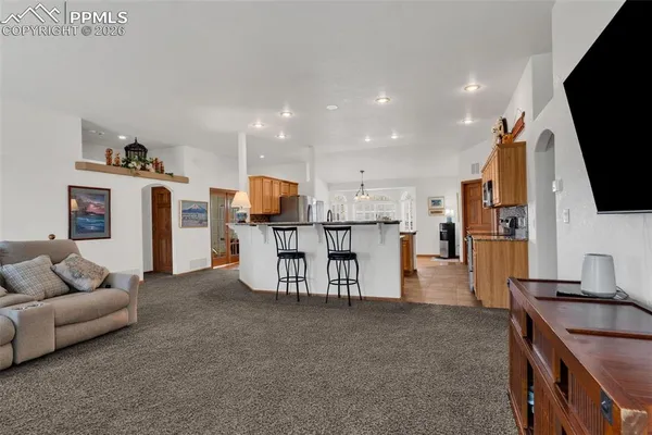 a kitchen with stainless steel appliances kitchen island granite countertop a table chairs sink and cabinets