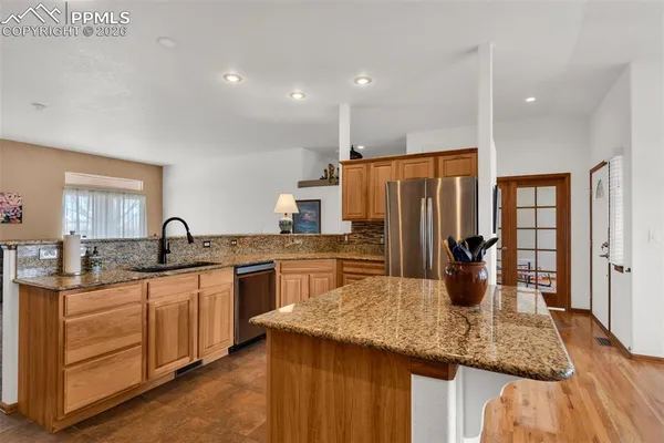 a kitchen with stainless steel appliances granite countertop a refrigerator a stove top oven a sink and dishwasher