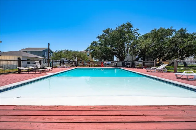 a view of a swimming pool with lawn chairs under an umbrella