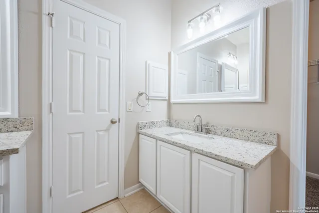 a bathroom with a granite countertop sink and a mirror