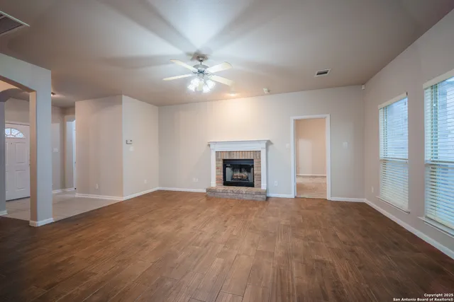 a view of empty room with wooden floor and fireplace