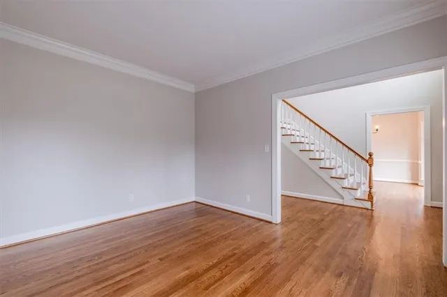 a view of an empty room with wooden floor and stairs
