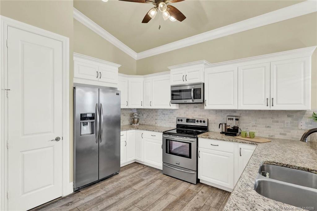 424 Southwest Camden Avenue Stuart, FL 34994 - Photo 13 of 58 a kitchen with stainless steel appliances granite countertop a refrigerator a stove a sink and white cabinets with wooden floor