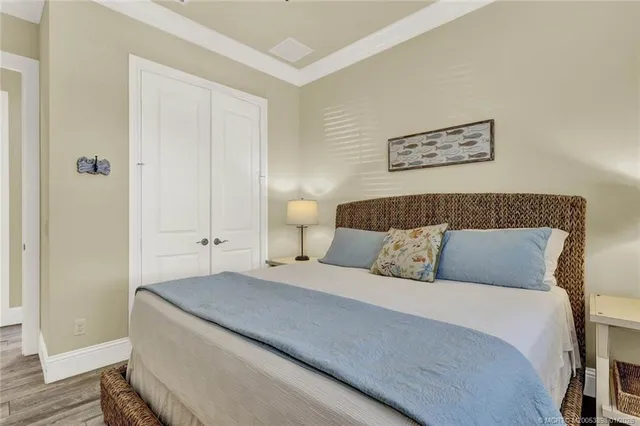 a bedroom with a bed a window and potted plant on the dresser
