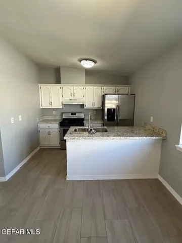 a living room with stainless steel appliances kitchen island granite countertop a stove a sink a refrigerator and cabinets