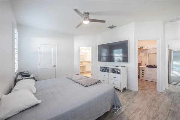 a bedroom with a large bed a flat tv screen and white walls