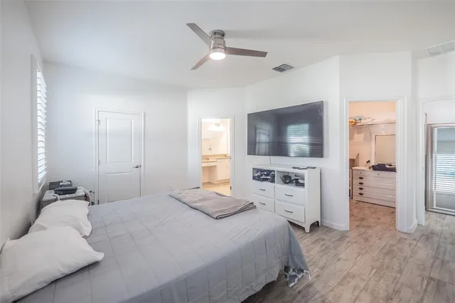 a bedroom with a large bed a flat tv screen and white walls