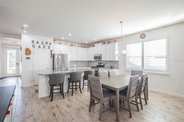 a white kitchen with a dining table chairs wooden floor and appliances