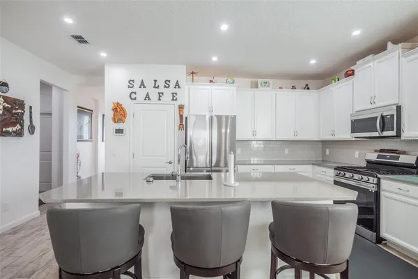 a kitchen with kitchen island a white cabinets and chairs