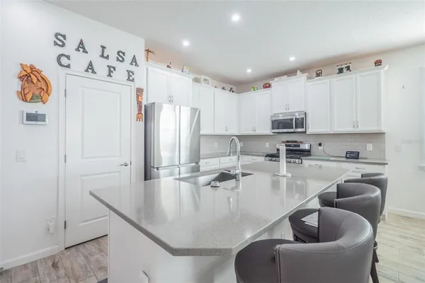 a kitchen with stainless steel appliances granite countertop a refrigerator a sink and white cabinets
