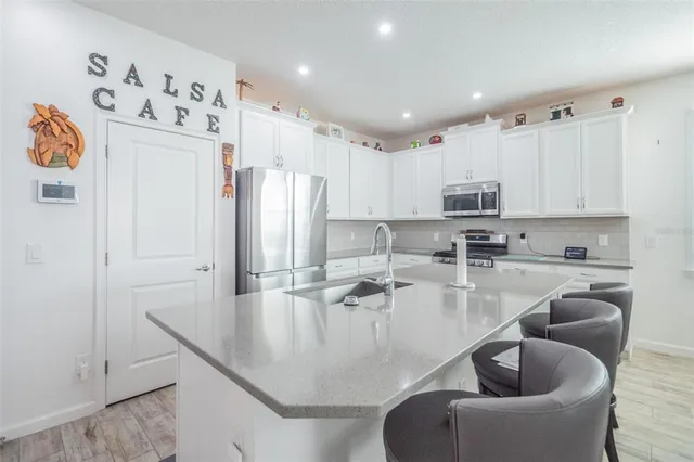 a kitchen with stainless steel appliances granite countertop a refrigerator a sink and white cabinets