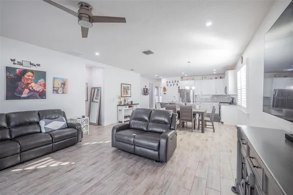 a living room with furniture kitchen view and a wooden floor