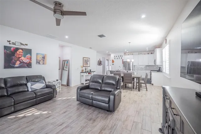 a living room with furniture kitchen view and a wooden floor
