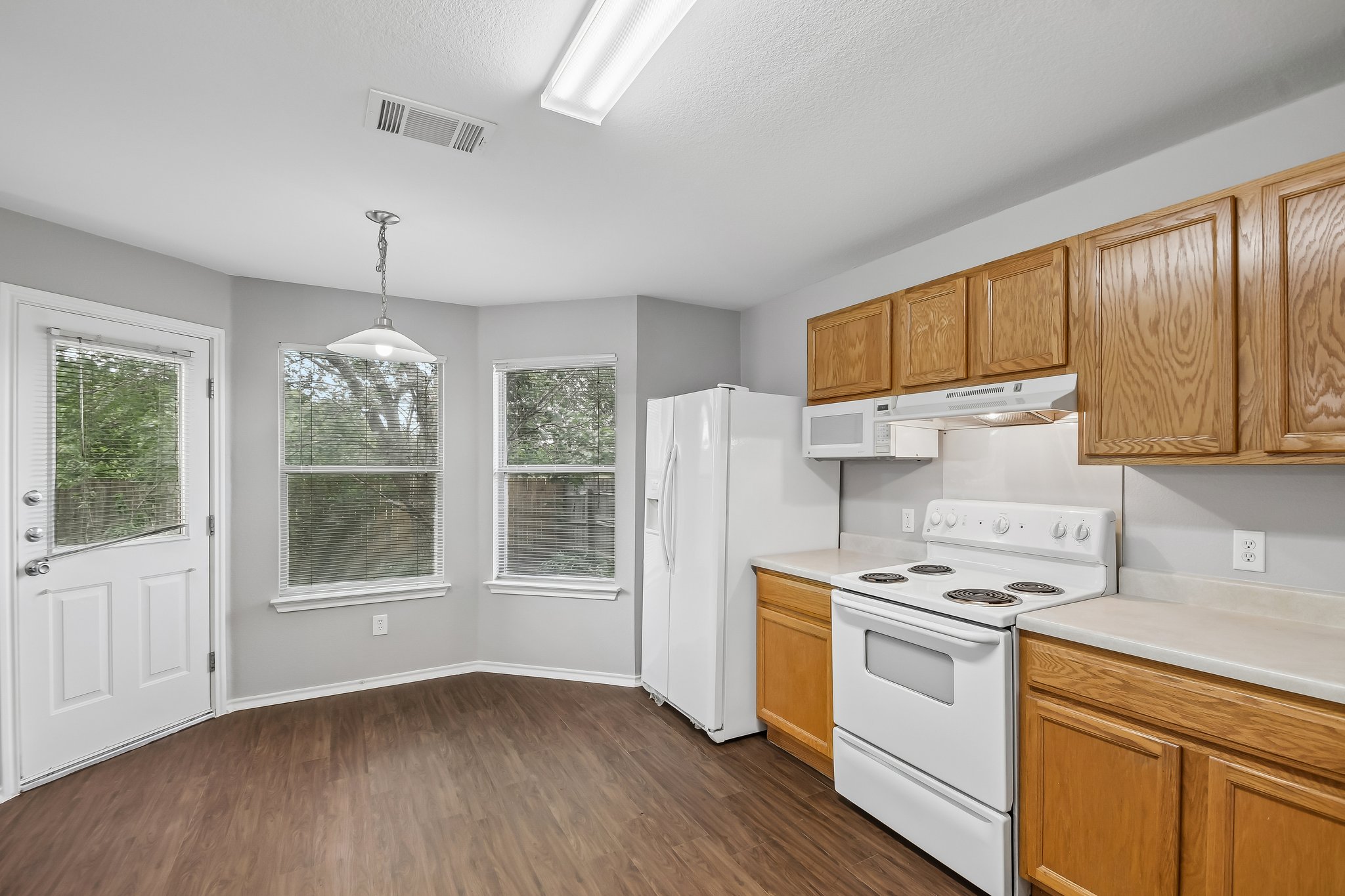 610 Lavaca Loop Elgin, TX 78621 - Photo 10 of 37 A well-lit kitchen with natural wood cabinetry and resilient flooring.
