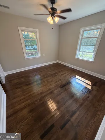 a view of an empty room with window and wooden floor