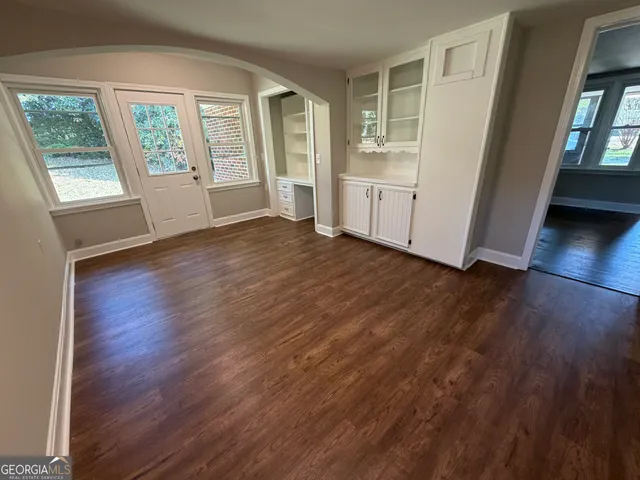 a view of an empty room with wooden floor and a window