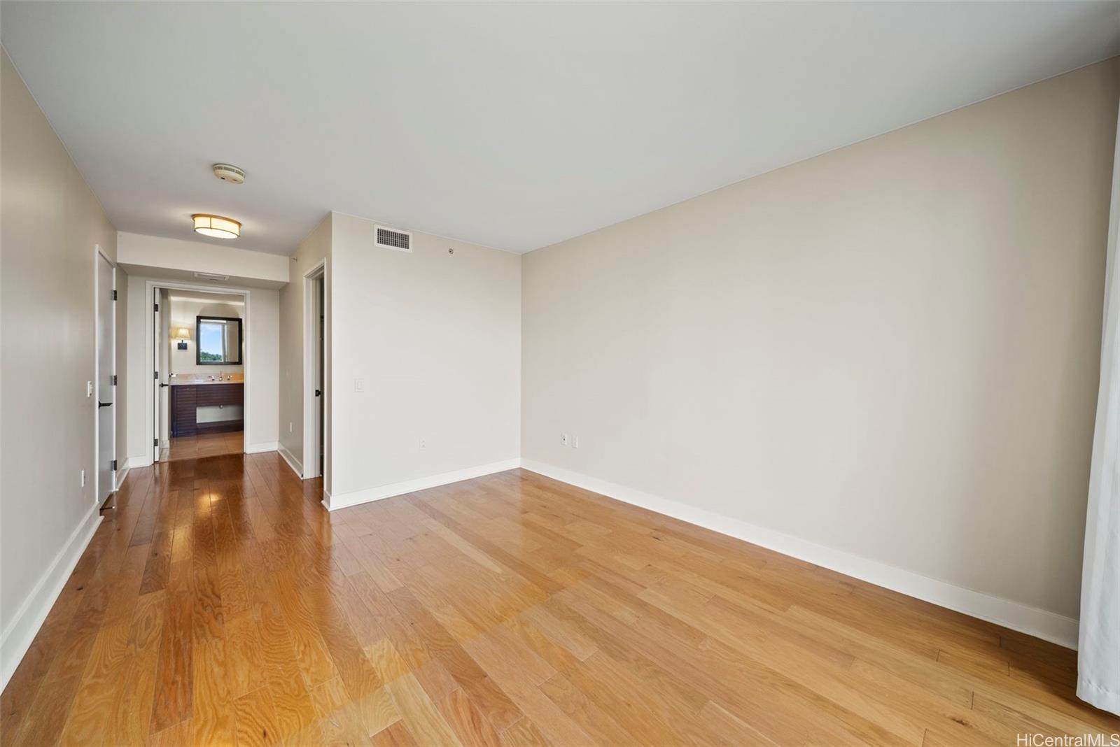 1551 Ala Wai Boulevard, Unit 504 Honolulu, HI 96815 - Photo 15 of 25 a view of an empty room and kitchen with wooden floor