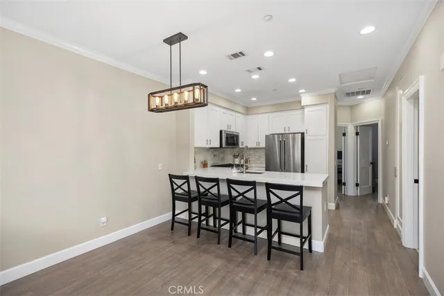 a kitchen with stainless steel appliances kitchen island granite countertop a dining table chairs and granite counter tops