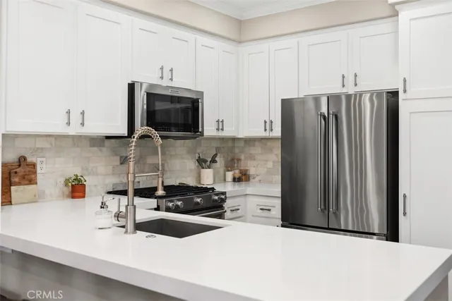 a kitchen with stainless steel appliances a refrigerator sink and white cabinets