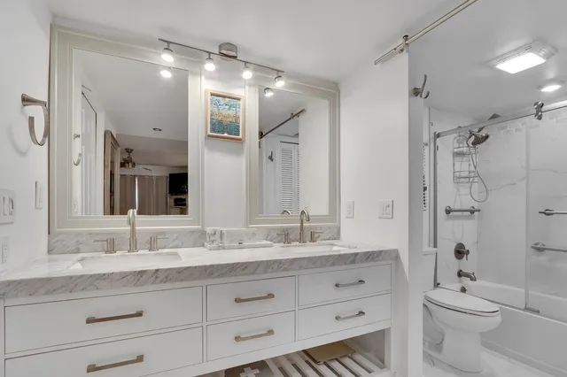 a bathroom with a granite countertop sink double vanity and a shower