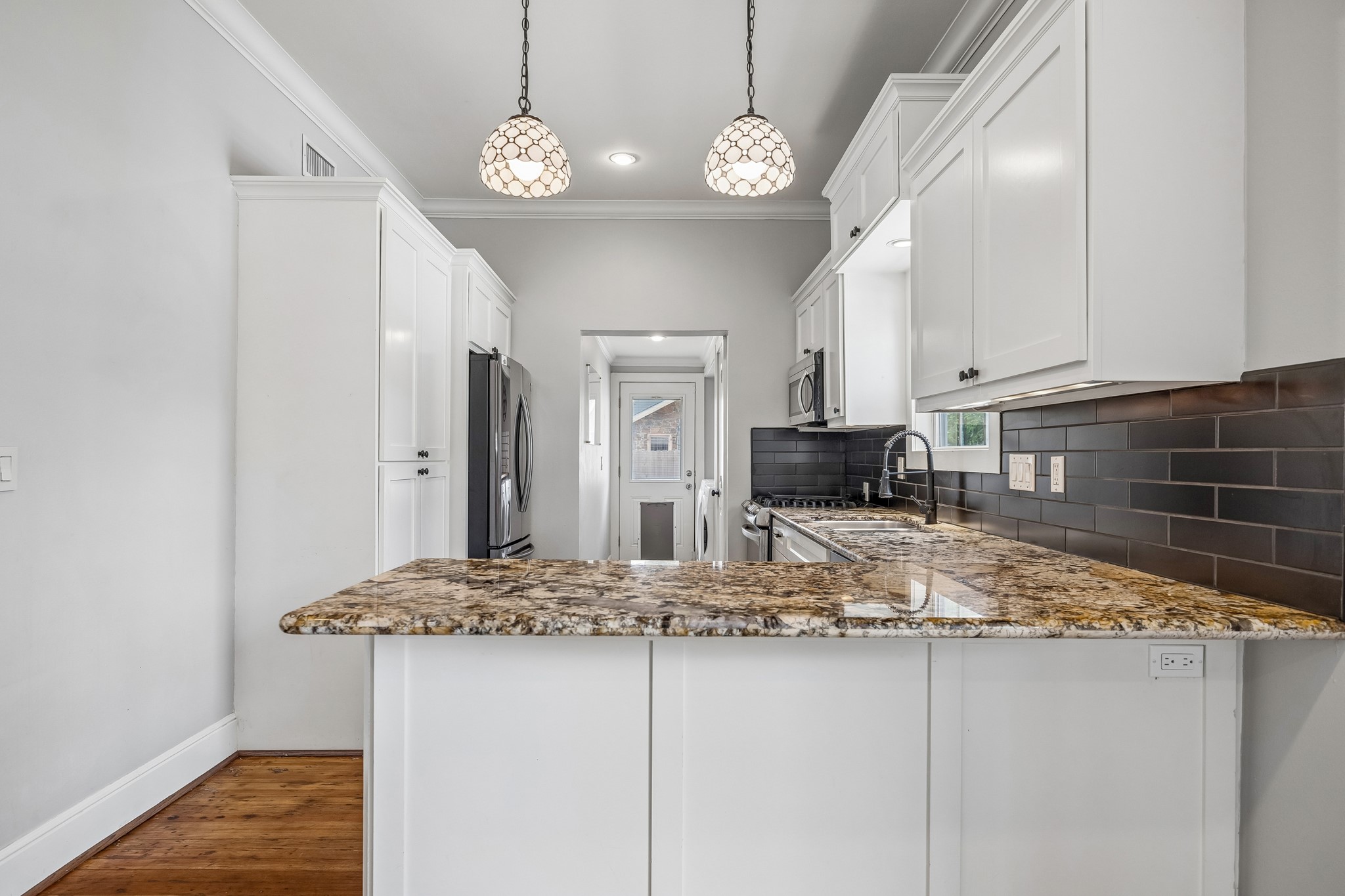4412 Rusk Street Houston, TX 77023 - Photo 11 of 44 Breakfast bar invites guests into exquisitely renovated kitchen, boasting granite counters, subway style backspalsh & recent high-end stainless appliances. Note stylish pendant lights above bar!