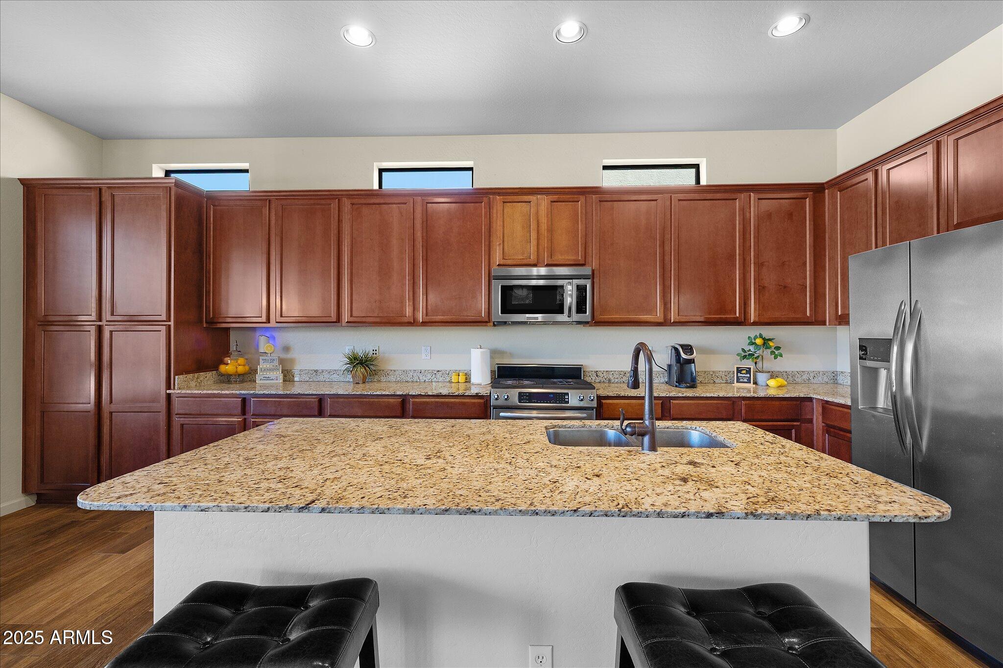 8536 East Inca Street Mesa, AZ 85207 - Photo 5 of 44 a kitchen with granite countertop kitchen island stainless steel appliances a sink a stove a refrigerator a center island and cabinets