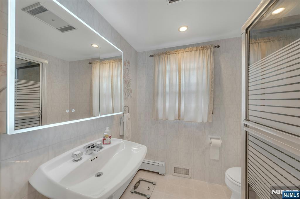 24 Cambridge Road Tenafly, NJ 07670 - Photo 17 of 31 a bathroom with a sink a toilet and shower