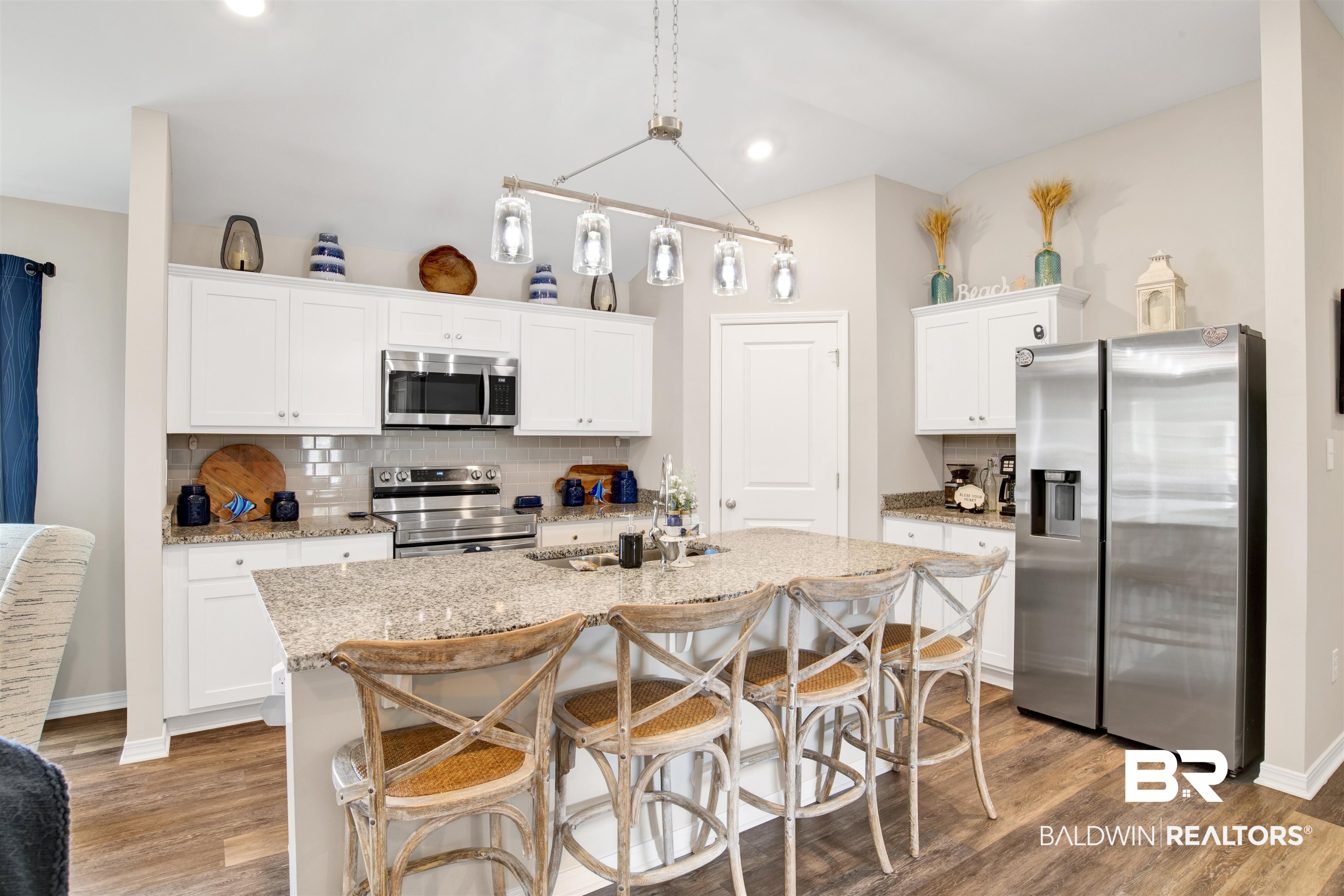 3097 Ingrid Lane Foley, AL 36535 - Photo 12 of 38 Kitchen with a breakfast bar area, decorative light fixtures, stainless steel appliances, decorative backsplash, and white cabinets