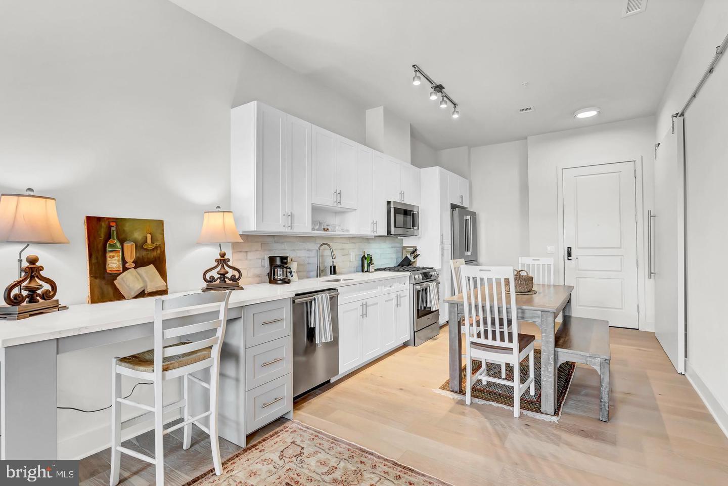 6803 Cameron Drive Northwest, Unit 514 Washington, DC 20012 - Photo 17 of 50 a kitchen with a dining table chairs and white appliances
