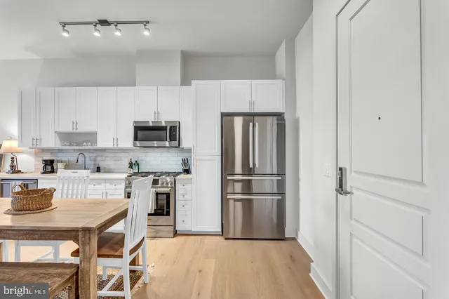 a living room with stainless steel appliances a stove a sink a microwave a refrigerator and cabinets