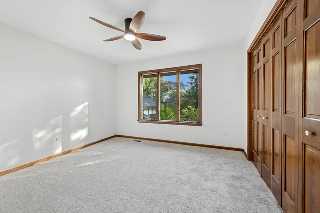 an empty room with windows and ceiling fan