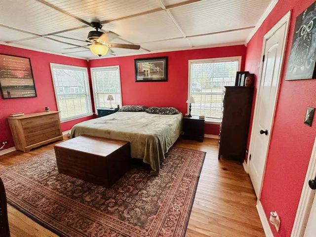 a bedroom with a bed wooden floor and window