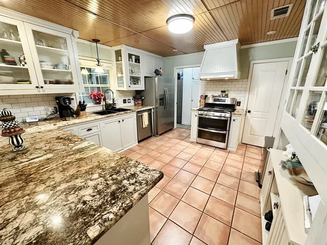 a kitchen with stainless steel appliances kitchen island granite countertop a sink stove and refrigerator