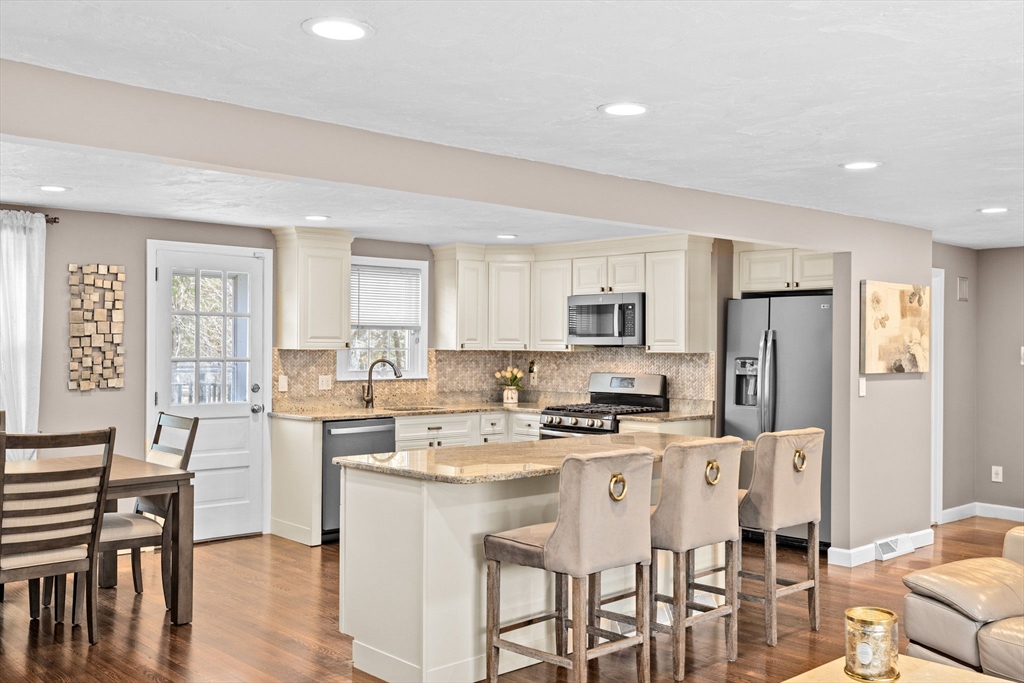 1368 Bay Road Stoughton, MA 02072 - Photo 10 of 42 a kitchen with stainless steel appliances kitchen island granite countertop a stove a refrigerator a sink a dining table and chairs