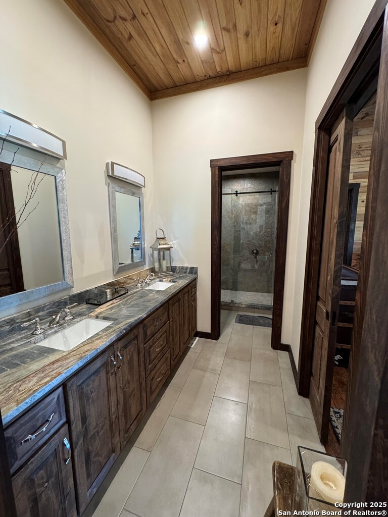 772 Luckenbach Road Fredericksburg, TX 78624 - Photo 42 of 86 a spacious bathroom with a granite countertop sink a mirror and a vanity