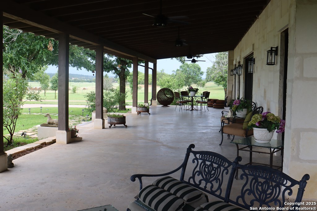 772 Luckenbach Road Fredericksburg, TX 78624 - Photo 7 of 86 a view of a patio with table and chairs potted plants with floor to ceiling window