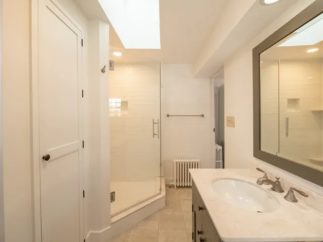 a bathroom with a granite countertop toilet a sink a mirror and a window