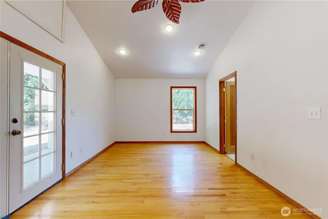 a view of an empty room with glass door and wooden floor